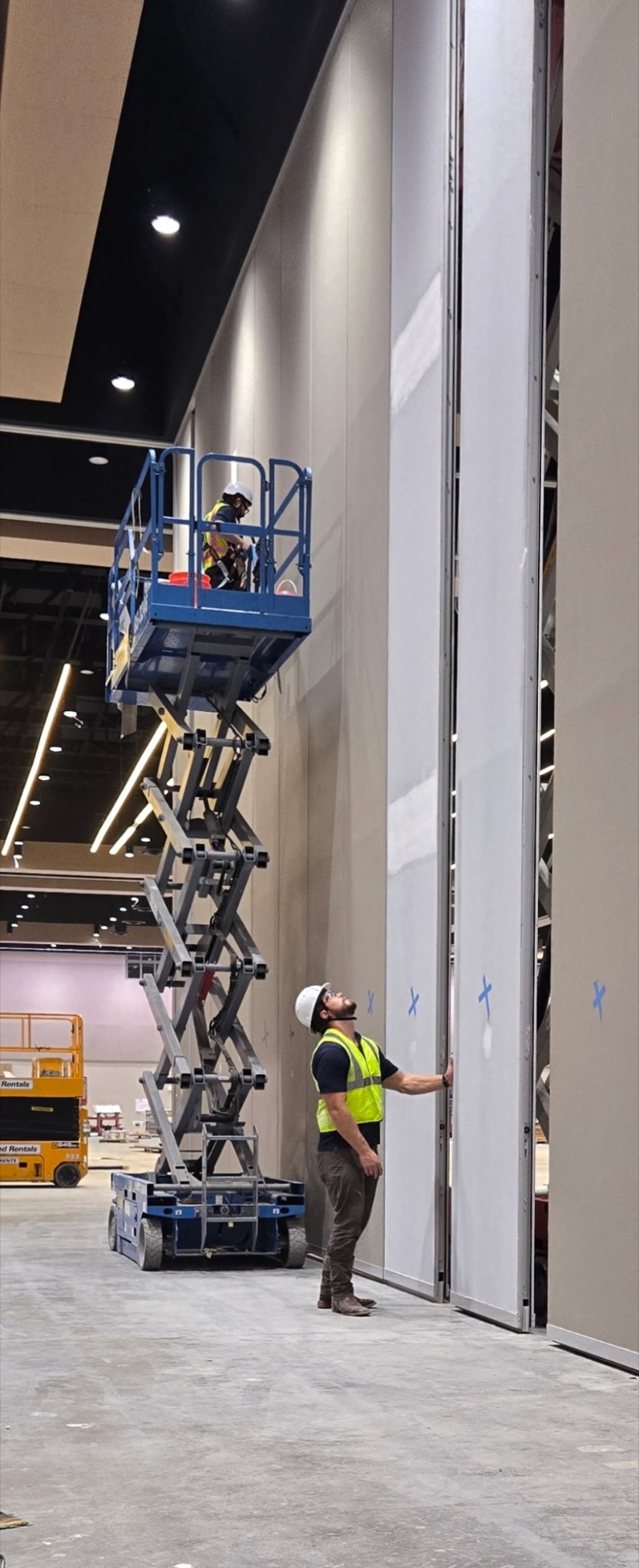 Technicians inspecting and restoring a 30-foot Moderco operable partition panel from a lift.