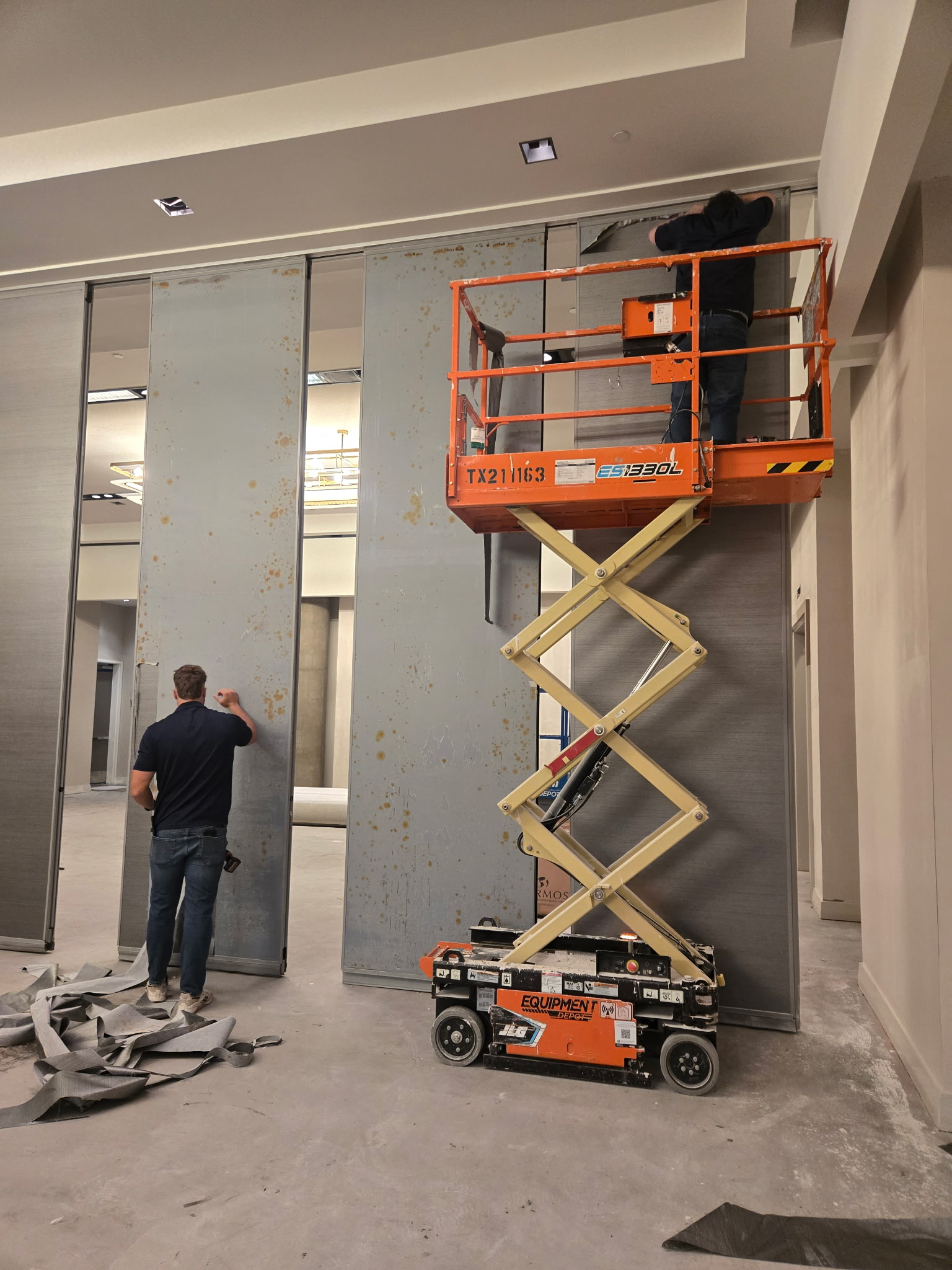 Technicians removing wallcovering from Hufcor operable partition panels to expose rust at W Austin.